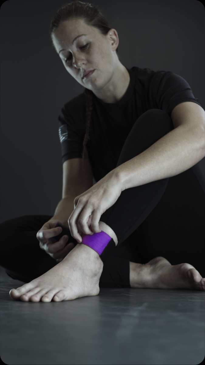 Athlete putting on a purple CombatCuff rank anklet